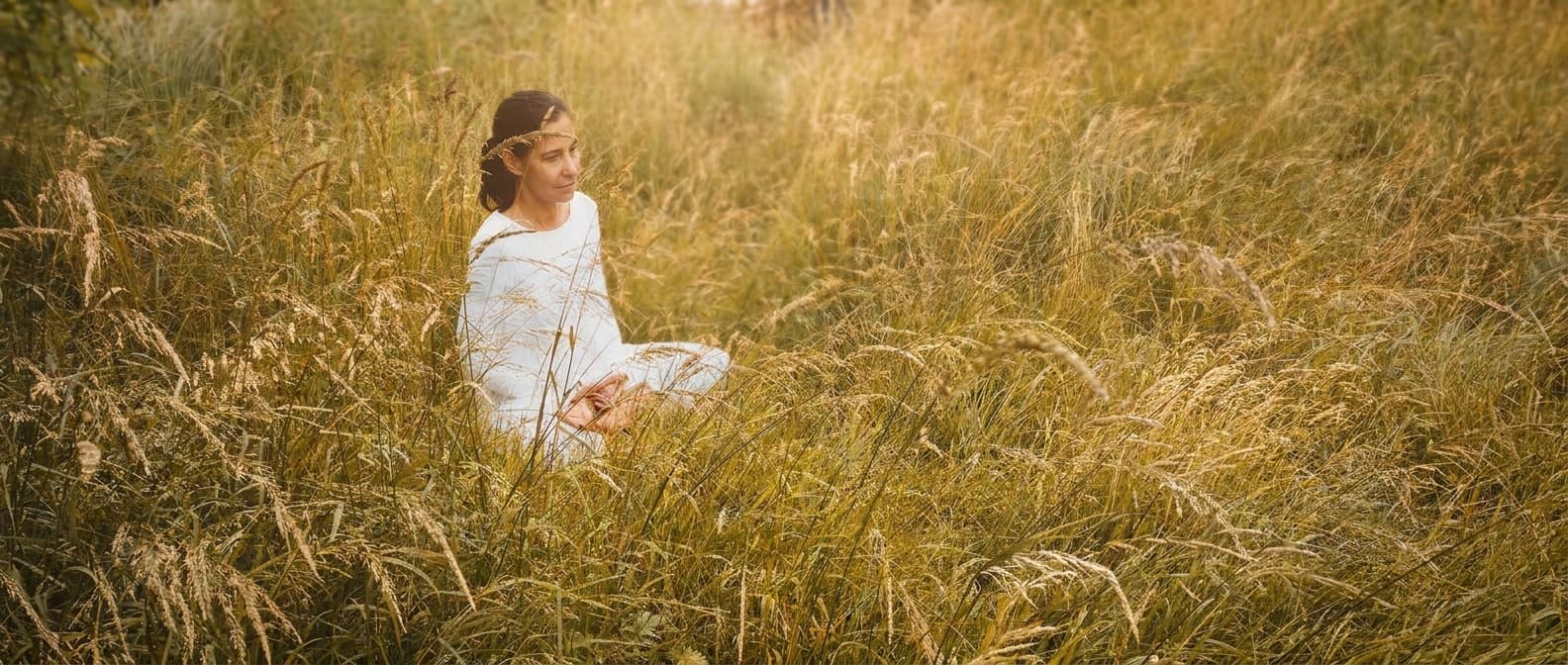 Lydia in Meditation im hohen, sonnendurchfluteten Gras