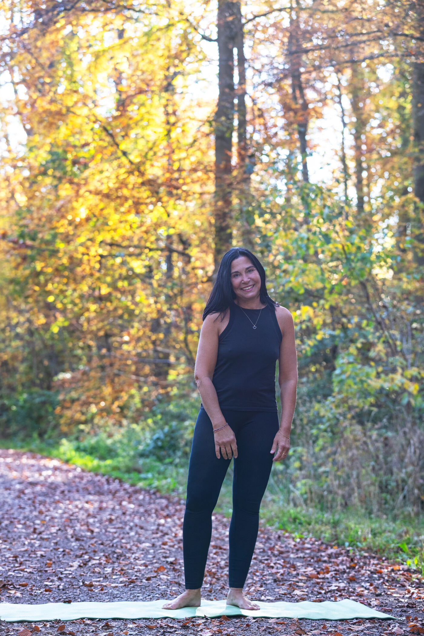 Lydia Schiano steht auf ihrer Yogamatte im herbstlichen Wald